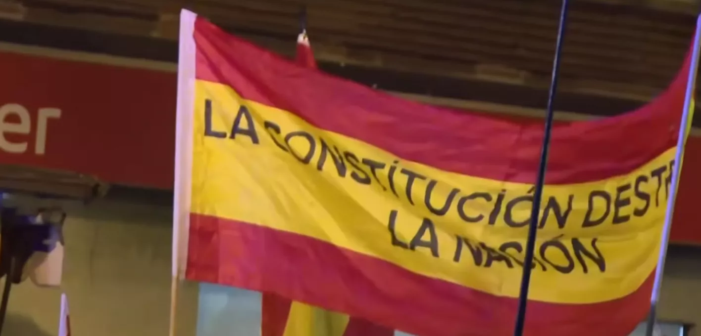 Bandera de España con el lema 'La Constitución destruye la nación', enarbolada durante las protestas frente a Ferraz.