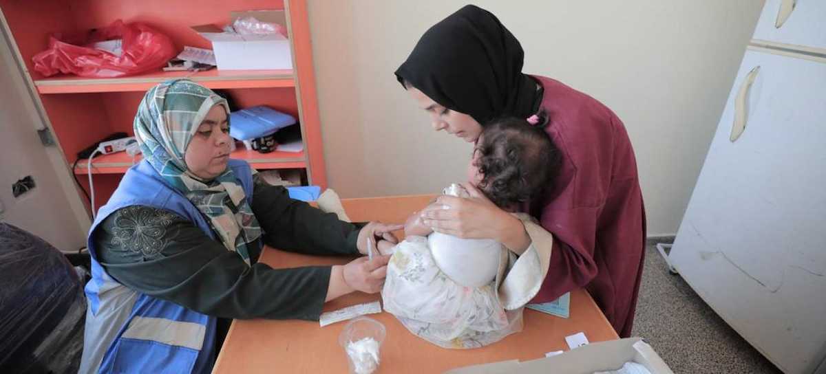 Una mujer atiende a un bebé en una clínica de la Franja de Gaza a la espera de un alto el fuego. | Foto: UNRWA