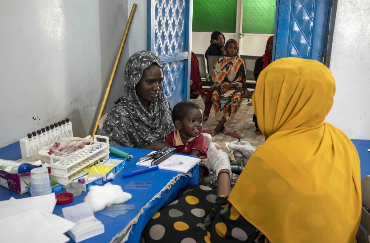 Una madre lleva a su hijo a hacerse un análisis de sangre a un establecimiento de salud para mujeres y niños en el campo de desplazados internos de Abu Shawk, en Darfur Septentrional. | Foto: OMS / Lindsay Mackenzie