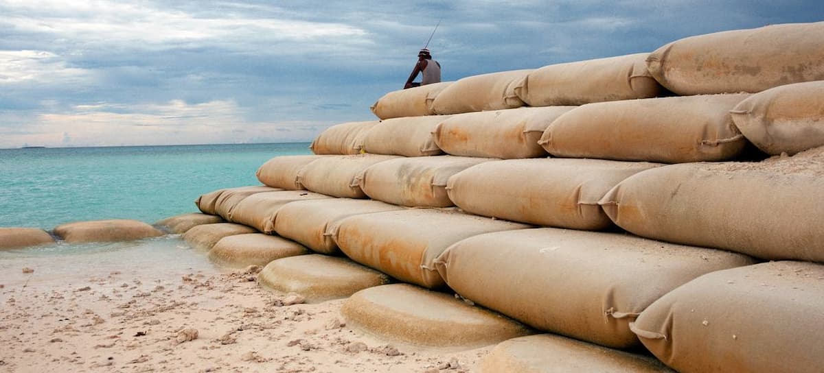 Un hombre pesca sentado sobre sacos de arena que protegen a Tuvalu, una nación insular del Océano Pacífico, contra la erosión marina desencadenada por la crisis climática. | Foto:  UNICEF/Lasse Bak Mejlvang