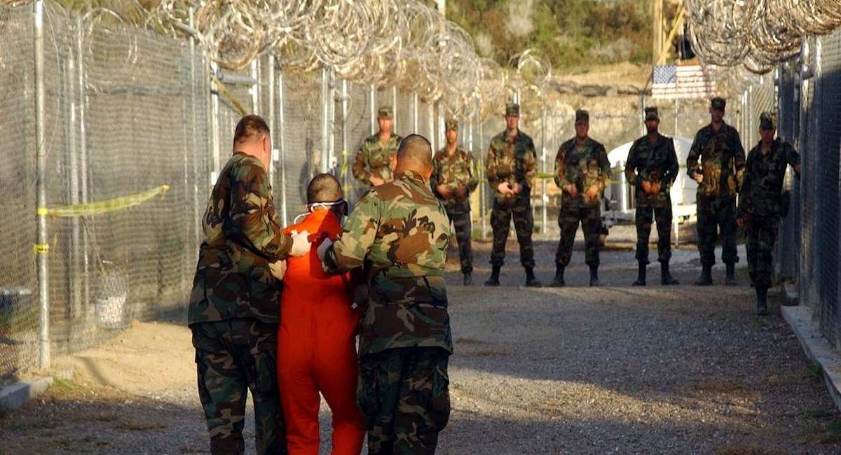 La policía militar del ejército estadounidense escolta a un detenido a su celda en el Campamento X-Ray en la Base Naval de Guantánamo, Cuba, en 2002. | Foto: Petty Officer Shane T. McCoy, U.