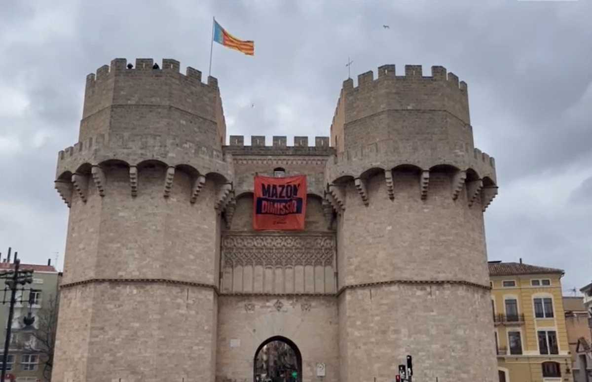 Valencianos descuelgan una pancarta contra Mazón en las Torres de Serranos.