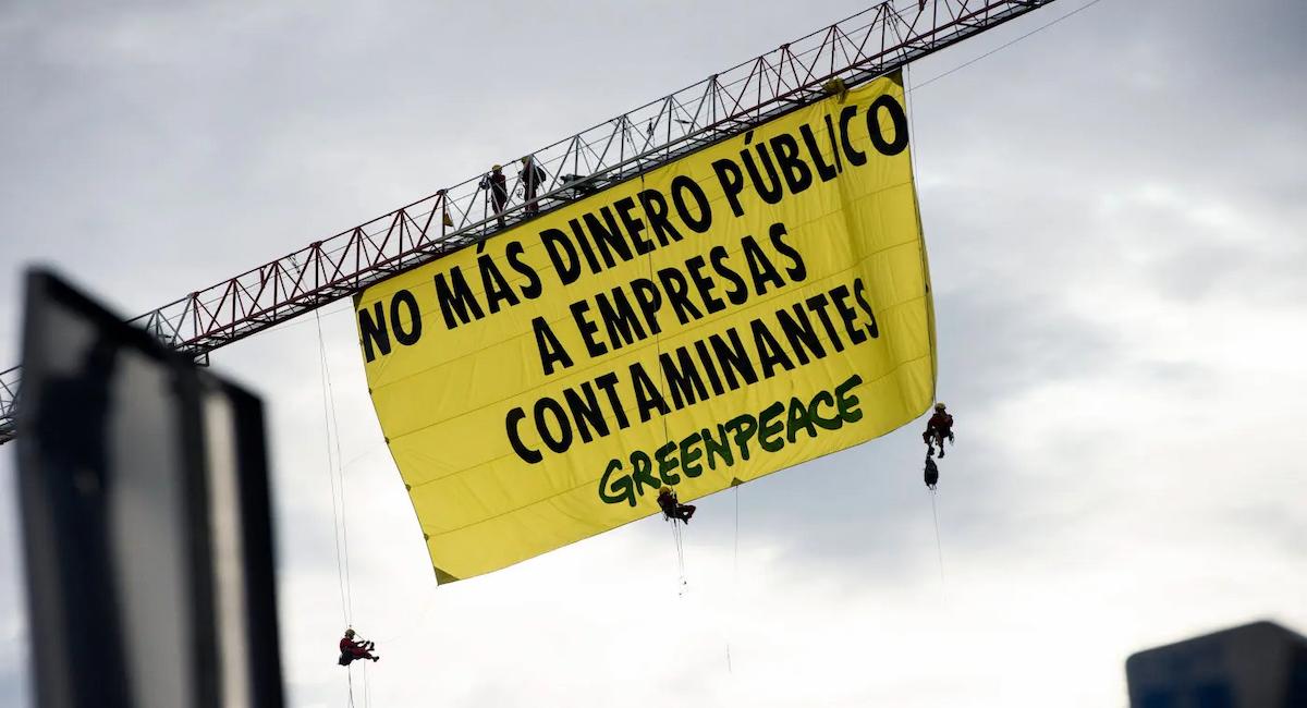 Activistas de Greenpeace encaramados a la sede del Banco Santander recuerdan al Gobierno de Sánchez que no destine más dinero público a empresas contaminantes.