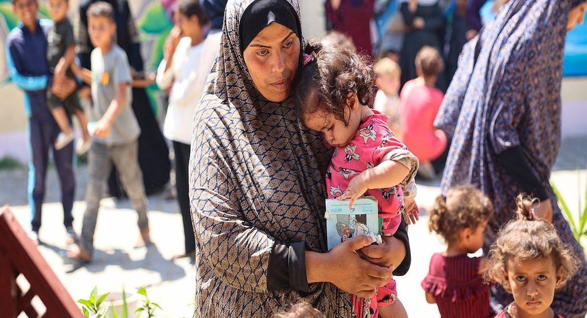 Una mujer sostiene a su hija mientras esperan durante una revisión nutricional en una clínica apoyada por UNICEF en la Franja de Gaza. | Foto: UNICEF/Eyad El Baba