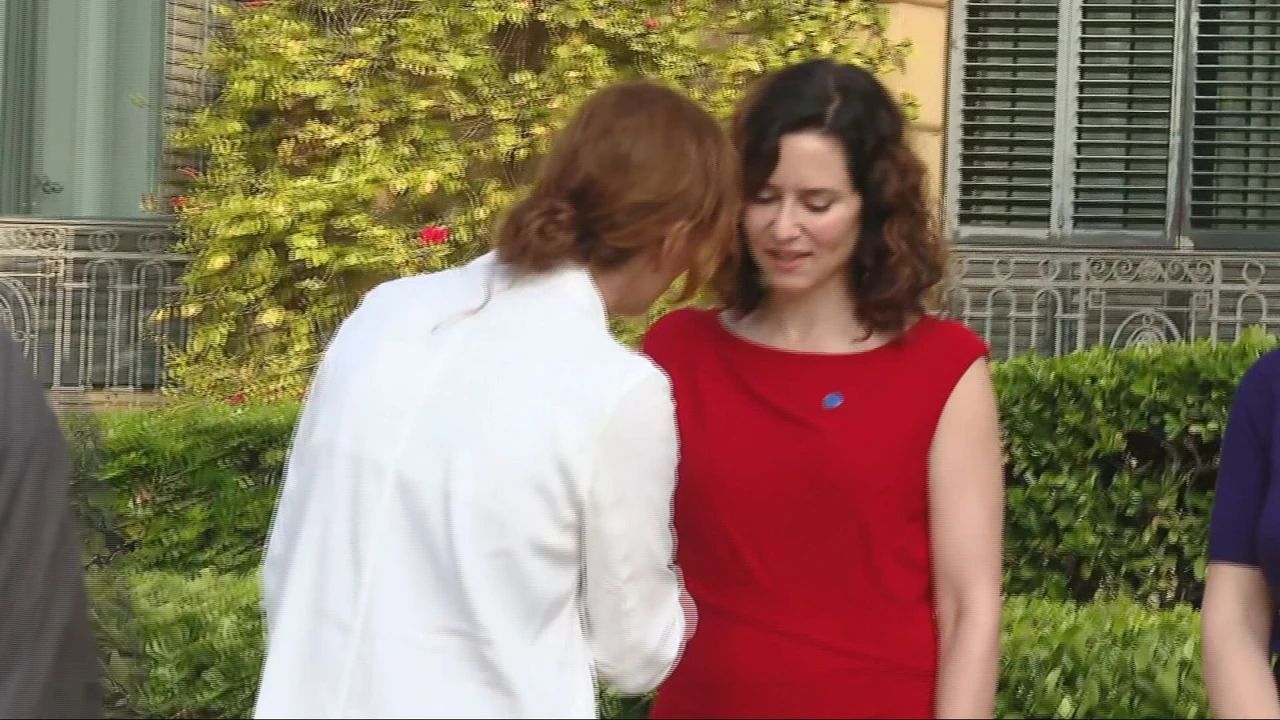 Monte García, ministra de sanidad, saluda a la presidenta de la comunidad de Madrid mientras ésta pierde los nervios