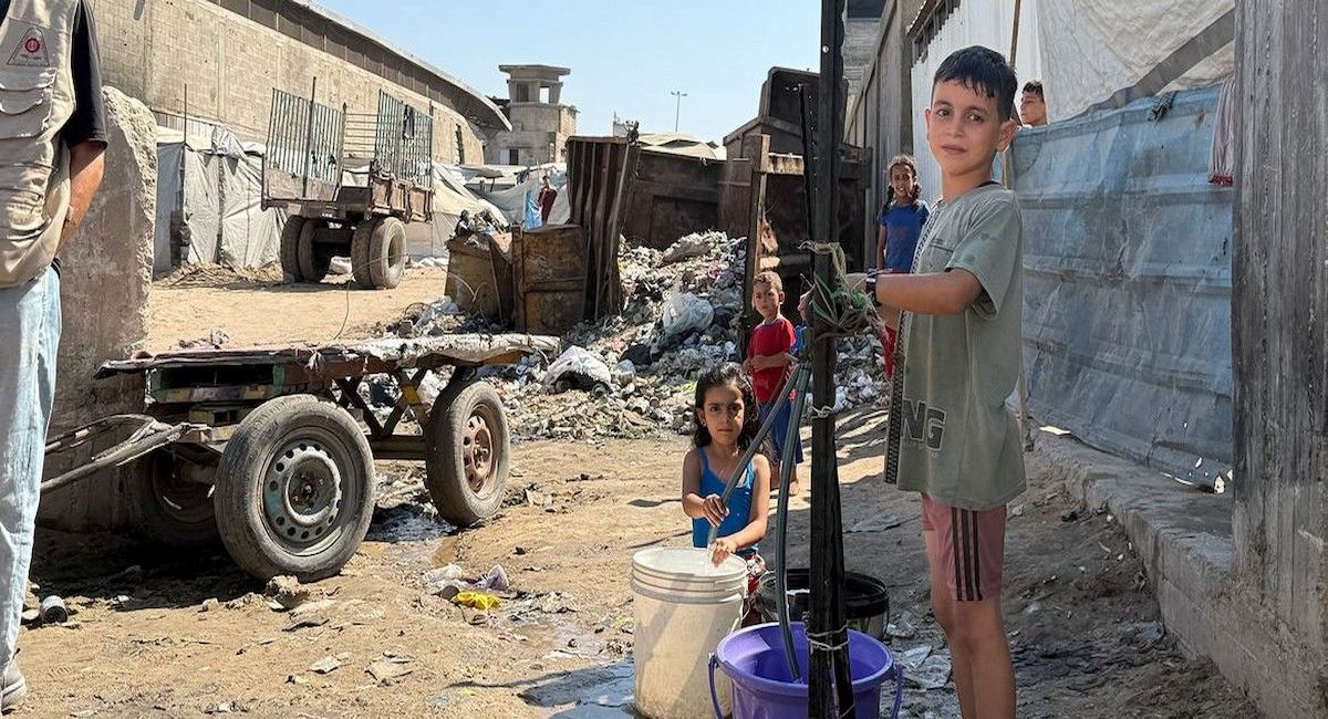 Unos niños recogen agua en el norte de Gaza. | Foto:  UNOCHA/Olga Cherevko