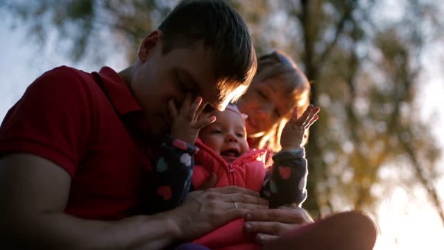 Happy family holding a baby in her arms. The sun is shining. View from below.