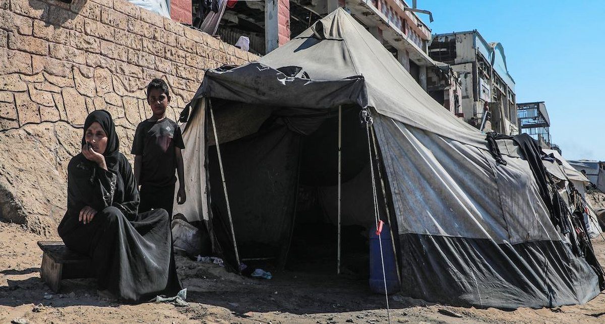 Una familia desplazada en Gaza frente a la tienda de campaña en la que se refugia. | Foto: UNICEF/Mohammed Nateel