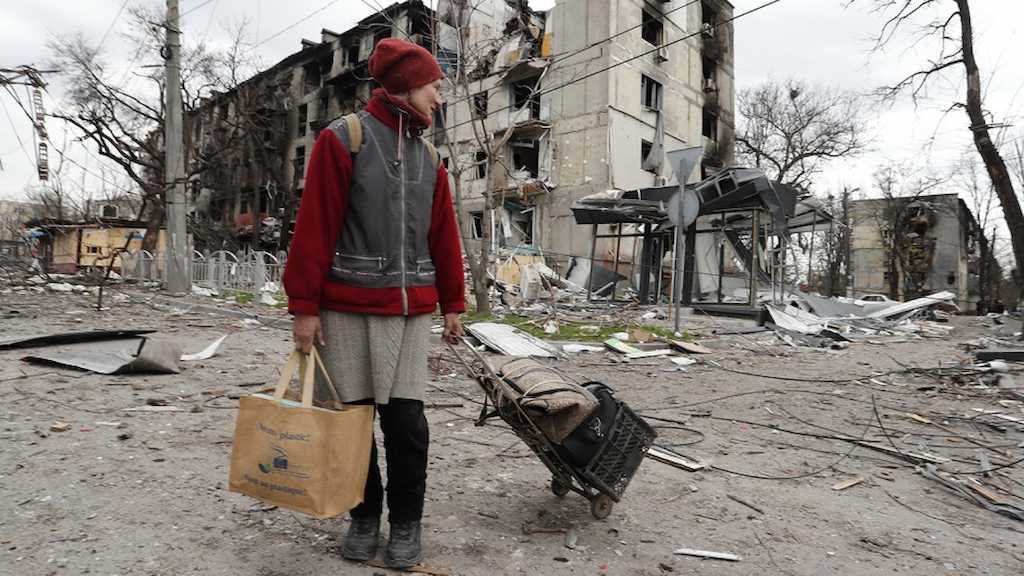 Una mujer observa los destrozos de la guerra.