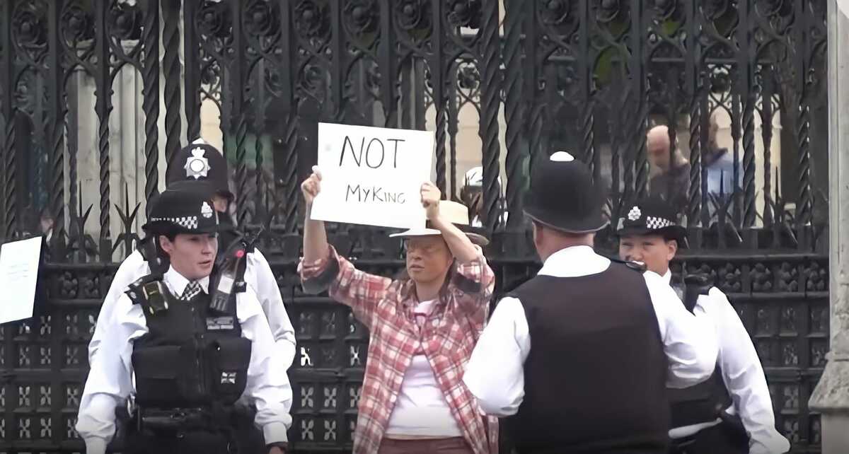 Una manifestante sostiene un cartel con el lema "No es mi rey".