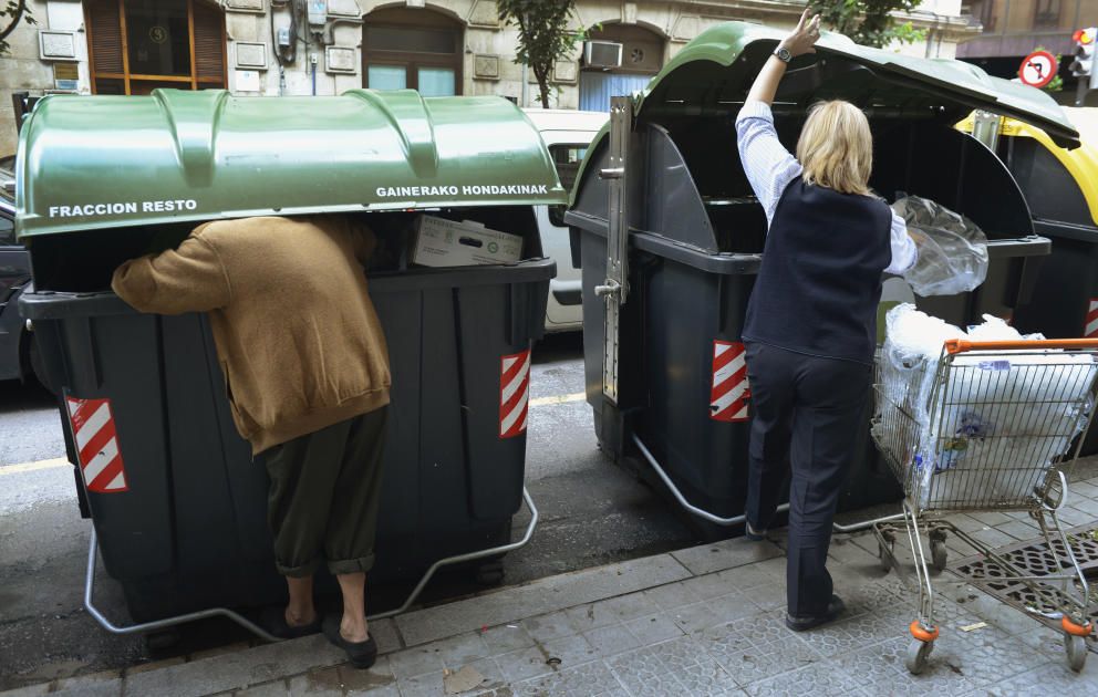 un-hombre-busca-comida-en-un-contenedor-de-bilbao-mientras-un-empleado-de-un-supermercado-tira-comida-en-el-de-al-lado-reuters.jpg