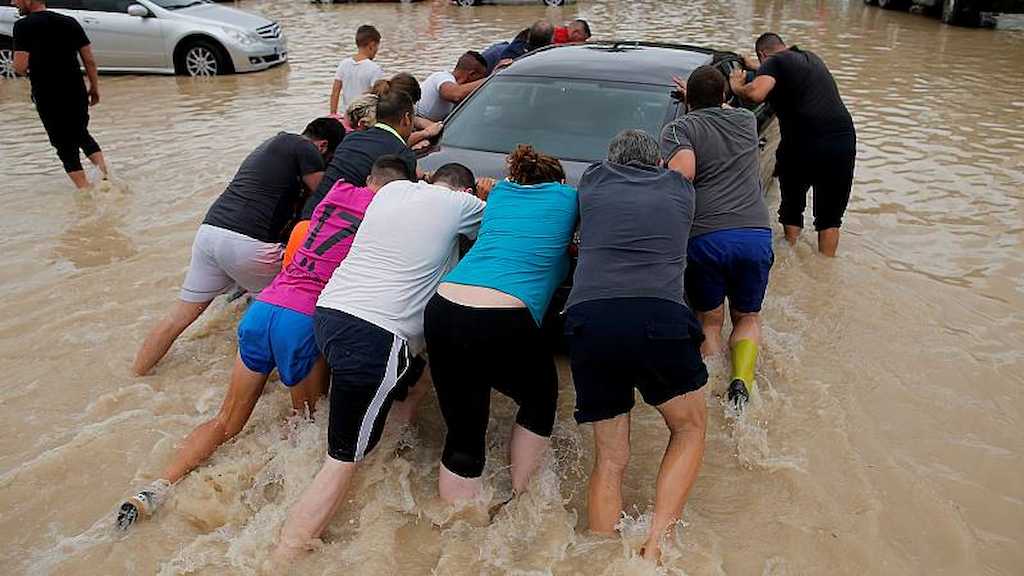 Un grupo de vecinos arrastra un coche tras las recientes riadas en la Comunidad Valenciana.