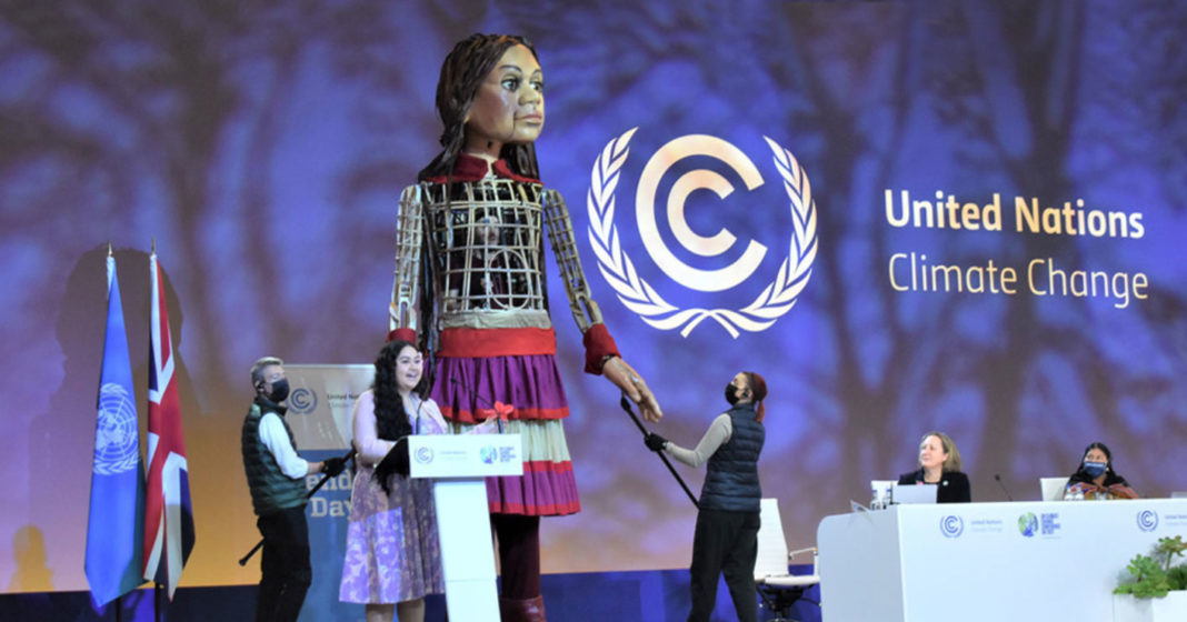 La activista samoana Brianna Fruean comparte protagonismo en la sesión plenaria de la COP26 con Little Amal, una marioneta gigante que representa a una niña refugiada siria. Foto ONU Laura Quinones