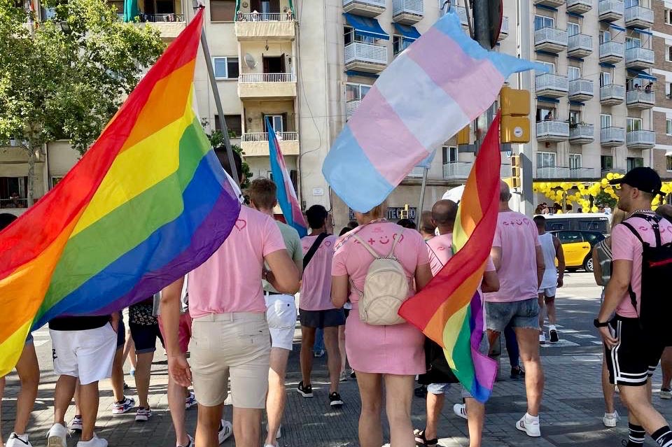 Jóvenes portando una bandera multicolor LGBT y otra de transgénero en una manifestación a favor de los derechos LGTBI.
