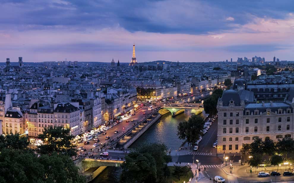 Foto aérea de la ciudad de París de noche con la Torre Eiffel de fondo.