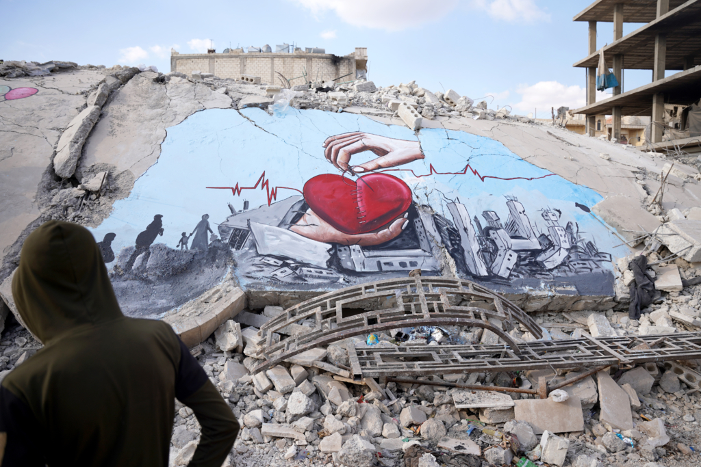 Alepo, Siria.— Grafiteros sirios pintan la lucha de los terremotos de febrero sobre las ruinas de un edificio derrumbado en Jindires. (Fotografía: Anadolu Agency/Getty Images)